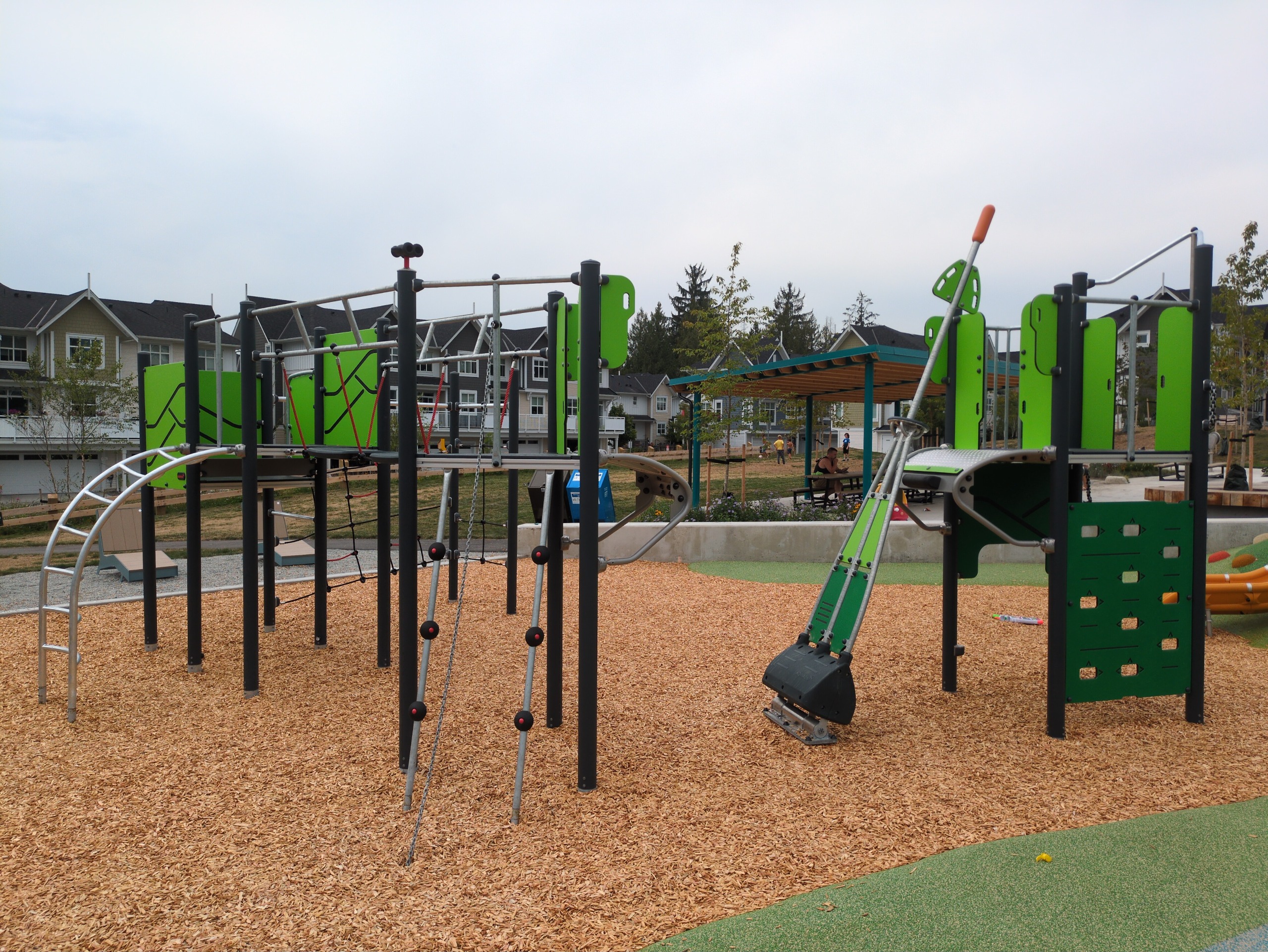 An intermediate play structure with a rope net climber and pivot arm cliff-rider