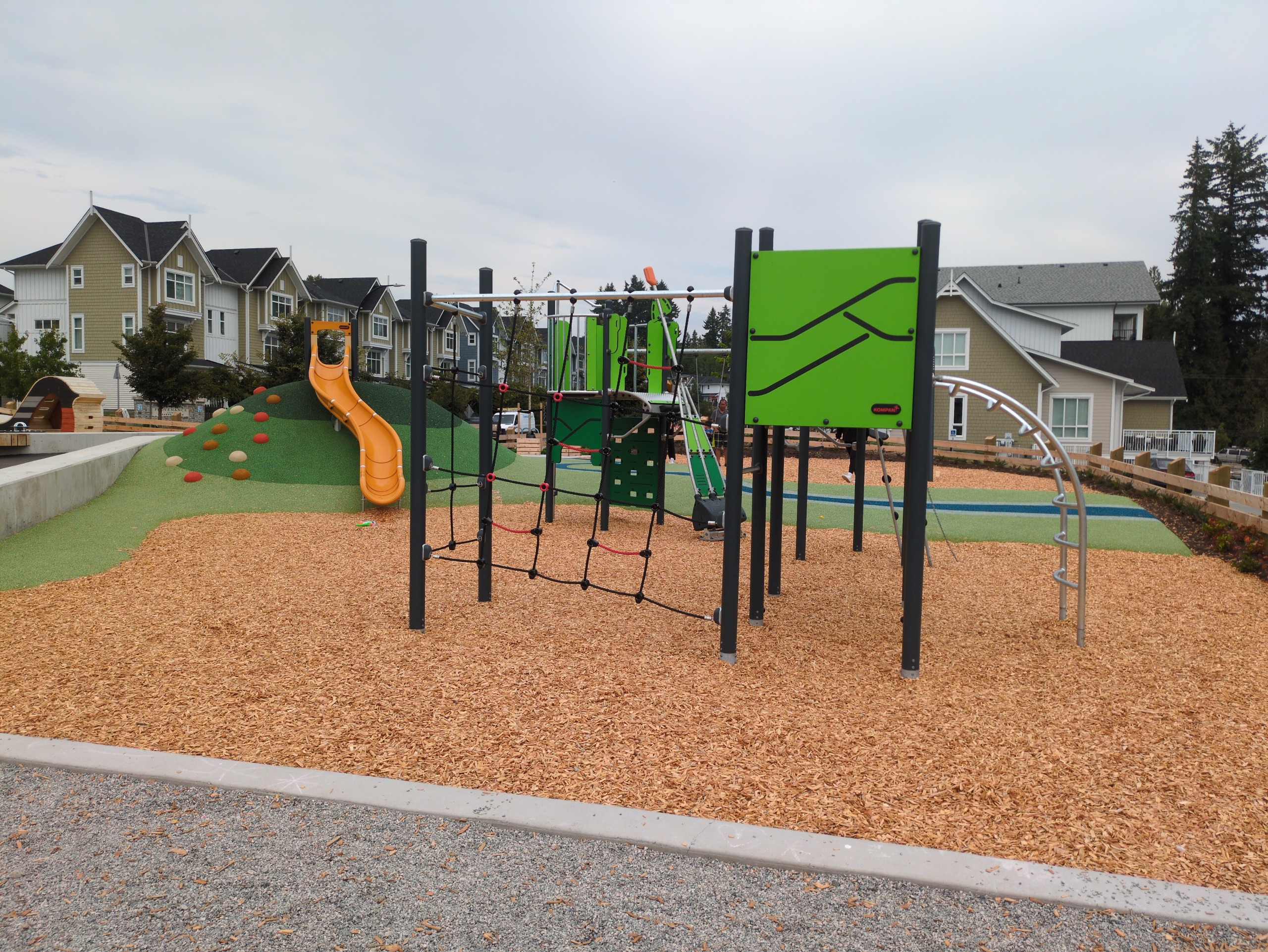 An intermediate play structure with a rope net climber and pivot arm cliff-rider