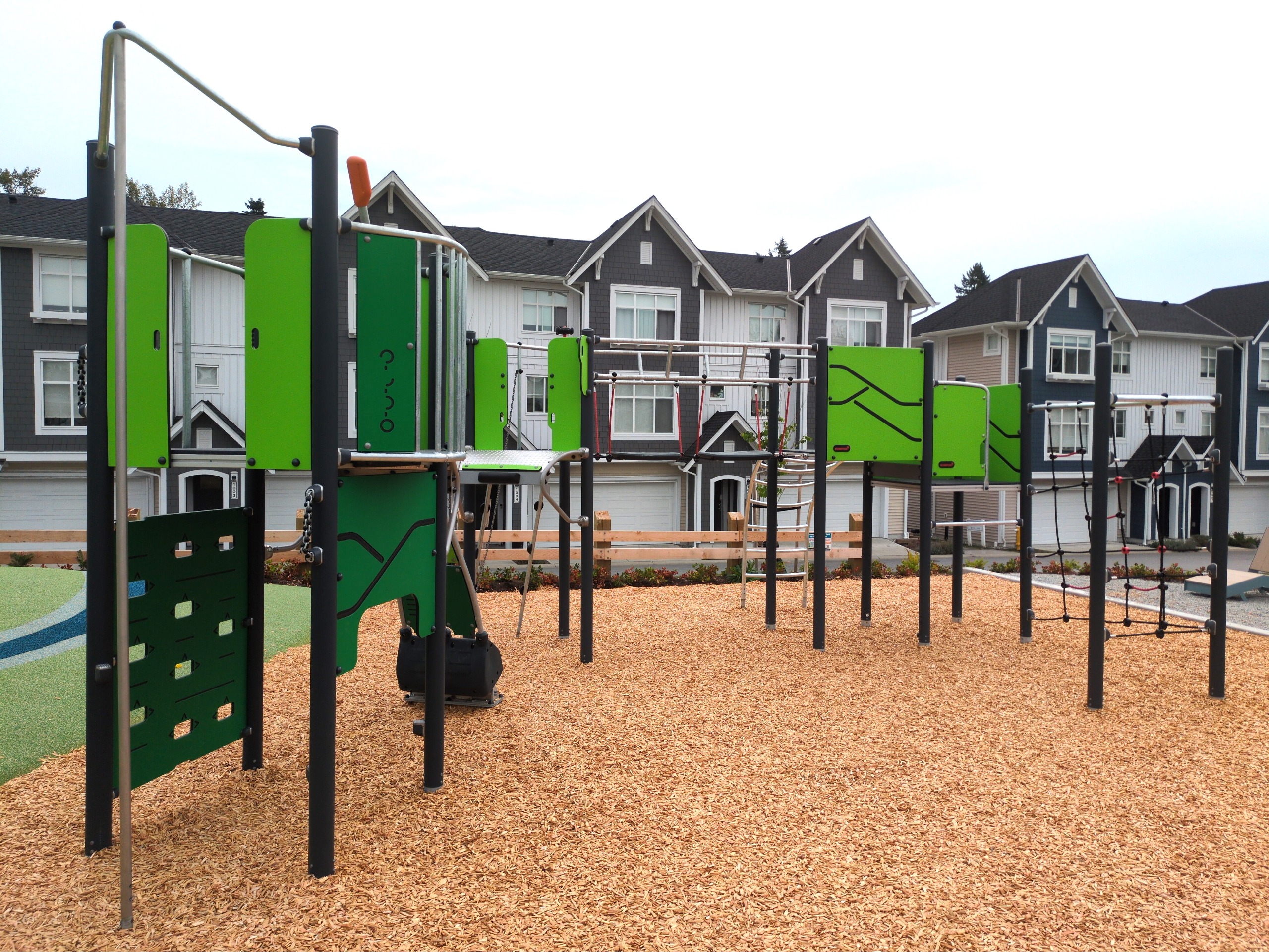 An intermediate play structure with a rope net climber and pivot arm cliff-rider